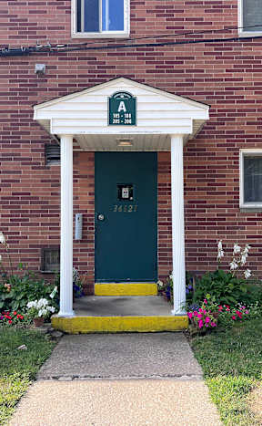 A brick building with a green door and a white awningat Emerald Village Apartments, Willoughby, OH