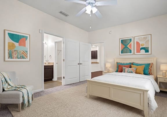 A bedroom with a bed, chair, and two pictures on the wall.