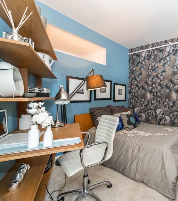 a bedroom with blue walls and a bed and a desk