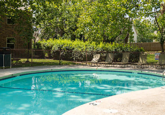 A sparkling swimming pool at Skyler Ridge Complex, surrounded by lounge chairs and lush landscaping.