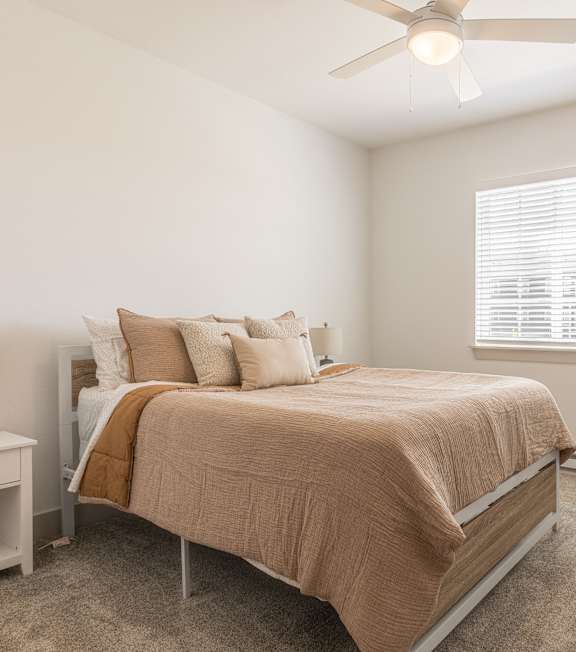 A bedroom with a bed, nightstand, and window.