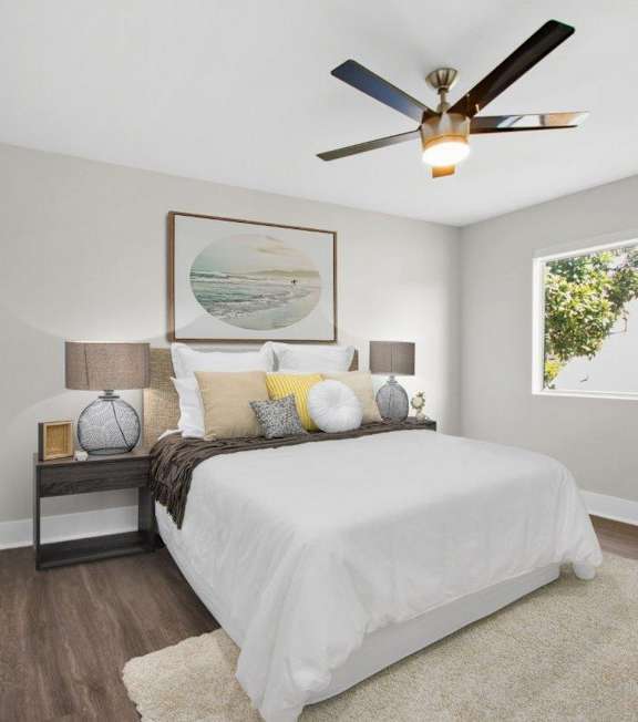 A bedroom with a white bed and a ceiling fan.
