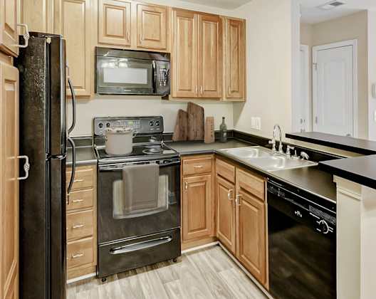 A kitchen with wooden cabinets and black appliances.