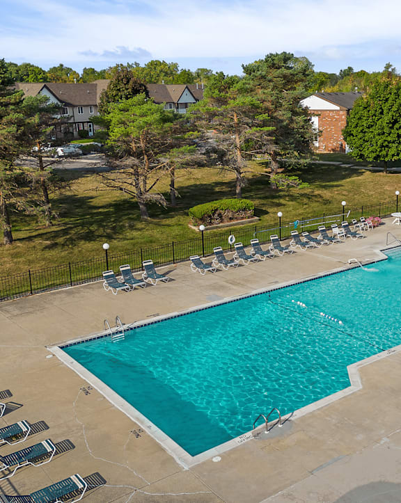 An aerial view of a pool surrounded by chairs and trees.