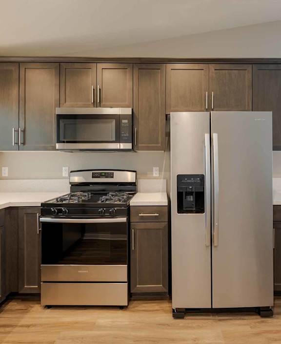 A kitchen with a stove, refrigerator, and microwave.