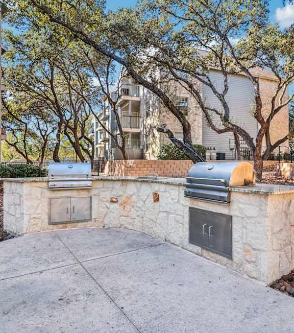 A stone wall with a fireplace and a trash can in front of it.