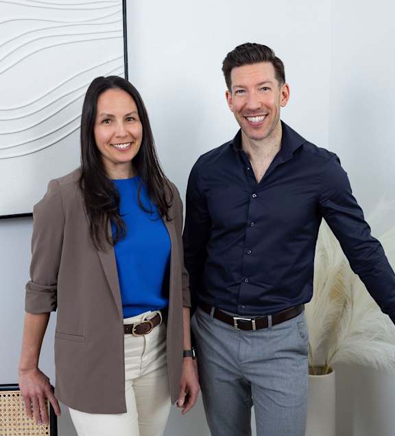 A man and a woman are standing in front of a white wall with a black and white abstract painting.