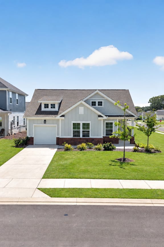 A brick house with a white garage door and a grey roof.