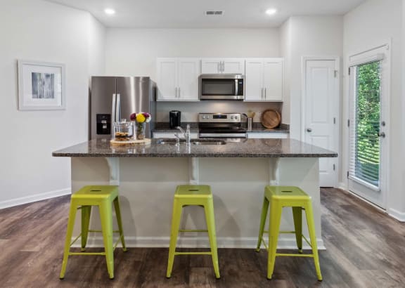 a kitchen with a large island with green stools