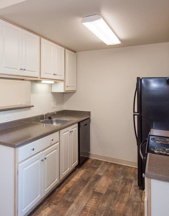 a kitchen with white cabinets and a black refrigerator