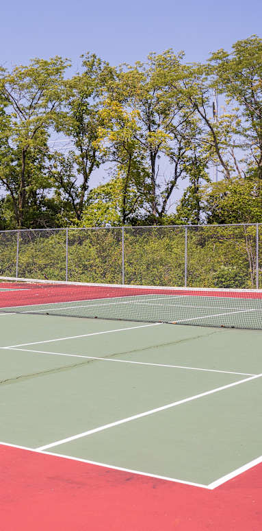 A well-maintained tennis court at Foxfire Apartments, surrounded by lush greenery.