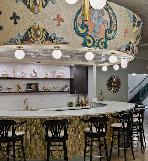 A bar with a gold and black counter and chairs.