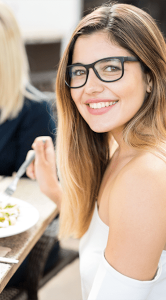 Three people are sitting at a table enjoying a meal and drinks.