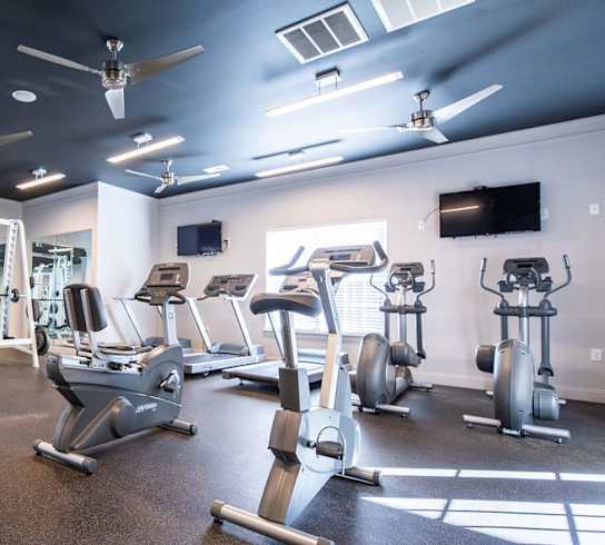 A gym with a variety of equipment including treadmills, weights, and exercise machines.