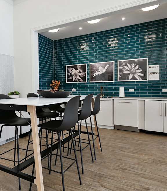 A kitchen with a table and chairs in front of a blue tiled wall.