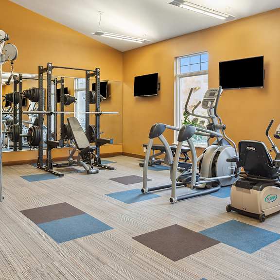 A gym with a variety of equipment including treadmills, weights, and exercise machines.
