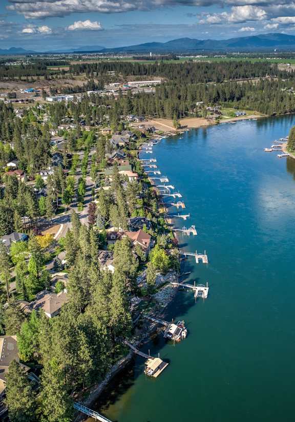 A serene aerial view of a lake surrounded by houses and trees.