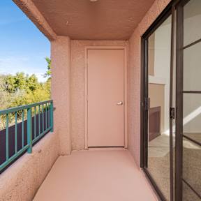 A balcony with a pink door and a green railing.