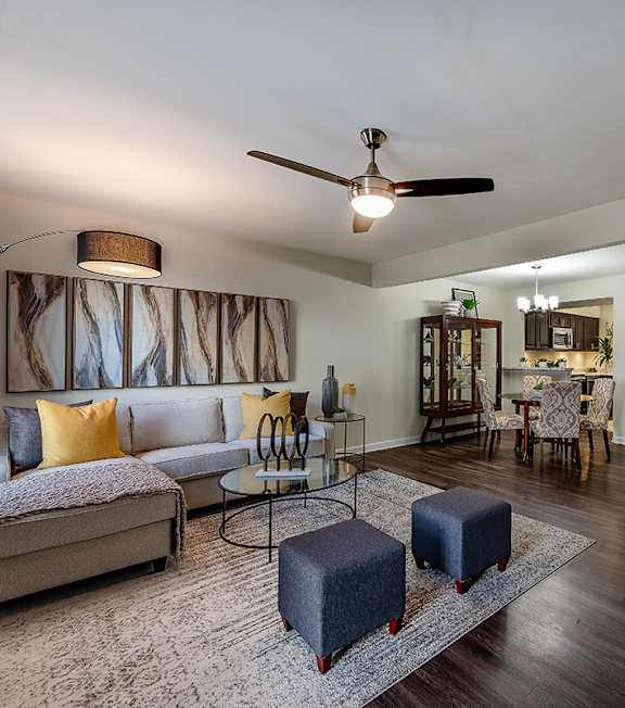 A living room with a grey sofa, a yellow sofa, a glass coffee table, and a rug.