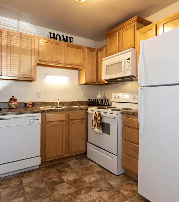 A kitchen with white appliances and wooden cabinets.