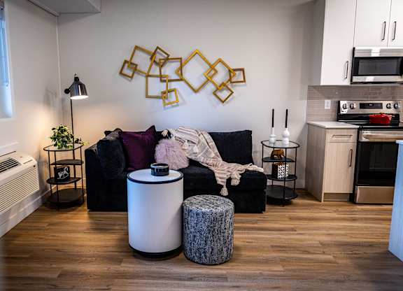 a living room with a black couch and a kitchen