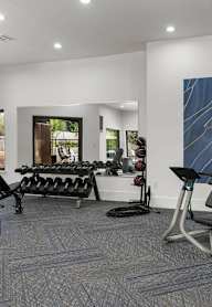 A home gym with a treadmill, weights, and exercise equipment.