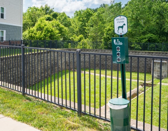 a black wrought iron fence with a green sign on it and a yard behind it