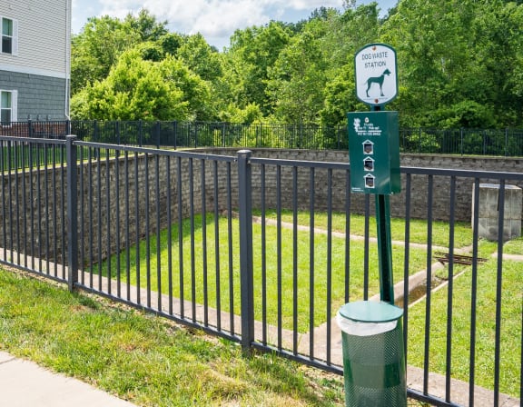 a black wrought iron fence with a green sign on it and a yard behind it