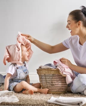 Mother Sitting on Floor with Child and Laundry Basket