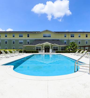 A large swimming pool in front of a hotel.
