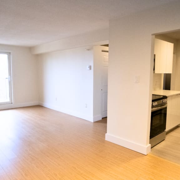 A modern kitchen with a stainless steel refrigerator and wooden flooring.