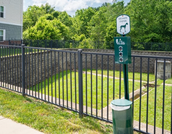 a black wrought iron fence with a green sign on it and a yard behind it