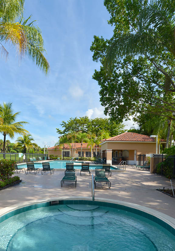 a swimming pool with chairs around it and a house in the background