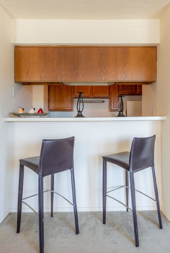 a kitchen with two stools in front of a bar with two chairs