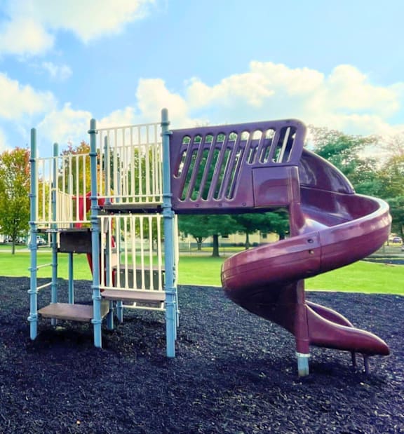 A playground with a red slide and a grey slide.