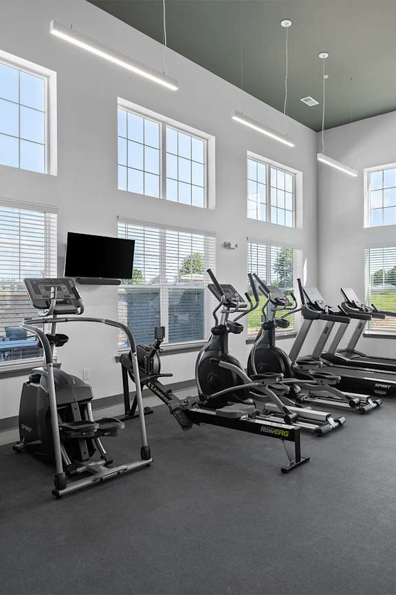 a gym with cardio equipment and windows on the wall