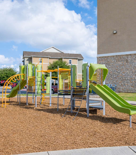 A playground with a green slide and a yellow and green play structure.