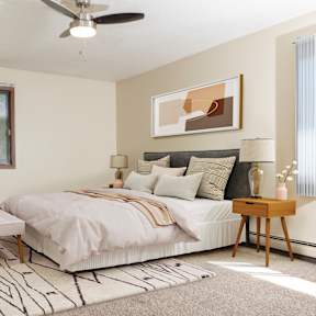 A bedroom with a bed, nightstand, and window.
