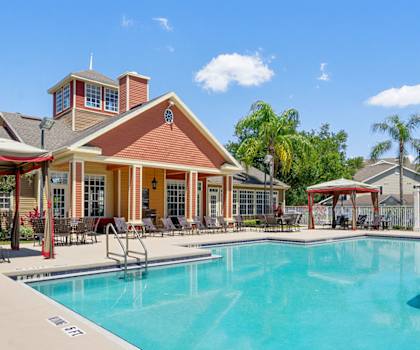 a pool with chairs and umbrellas in front of a building at Bella Vista on Park, Plant City
