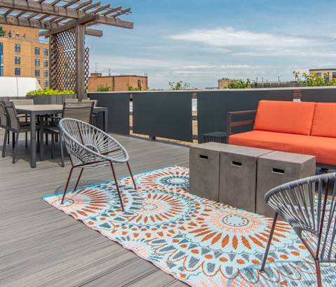 a rooftop patio with a couch and tables and a pergola