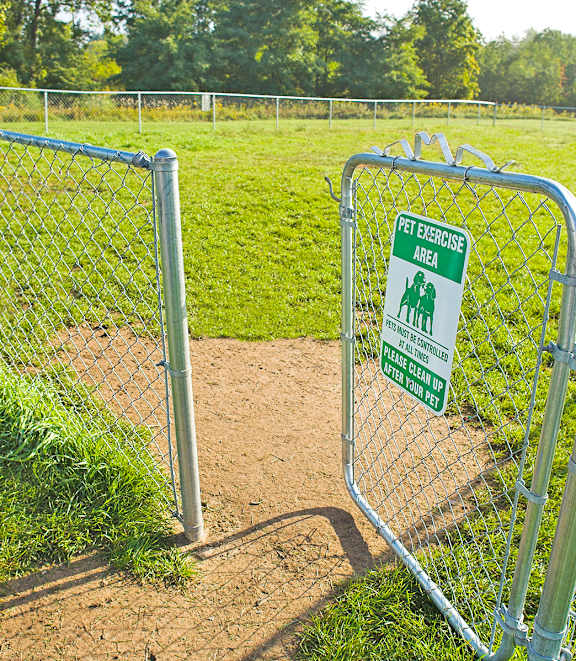 A green sign on a fence that says "Pet Exercise Area".
