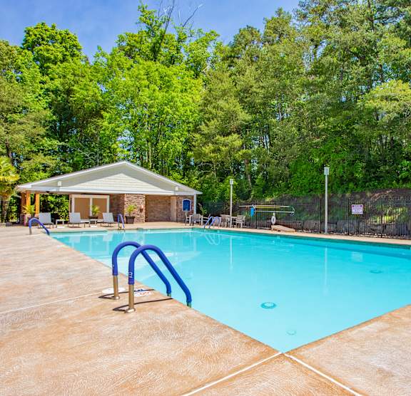 A large swimming pool surrounded by trees and a small building. at West Pointe Apartments, Apartments, Burlington, NC