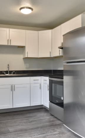 an empty kitchen with stainless steel appliances and white cabinets