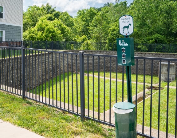 a black wrought iron fence with a green sign on it and a yard behind it