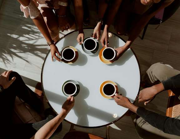 A group of people sitting around a table holding cups.