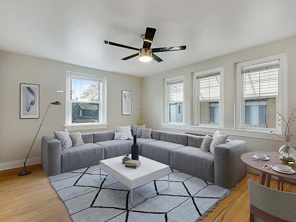 A living room with a grey couch, a white coffee table, and a ceiling fan.