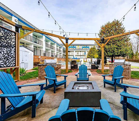 an outside patio with blue chairs and a fire pit