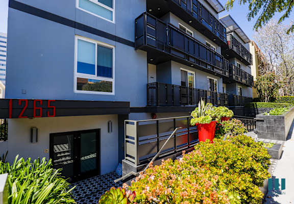 an apartment building with a blue exterior and balconies and plants