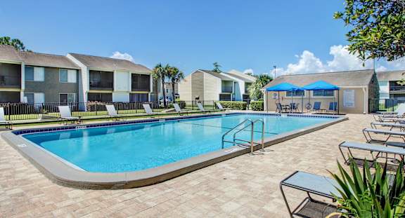 A swimming pool surrounded by lounge chairs and umbrellas.