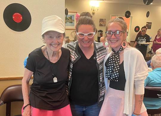 Three women wearing pink skirts at River Commons Senior Living, California